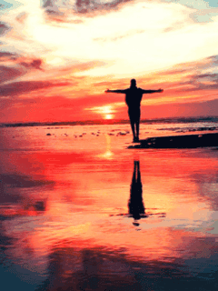 Peaceful person standing with arms outstretched at sunset reflecting on the ocean, spiritual reflection, mindfulness, tranquility, meditation, beach relaxation.