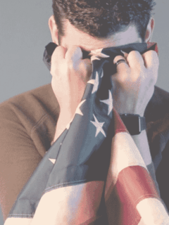 Patriot holding an American flag close, symbolizing faith and national pride.