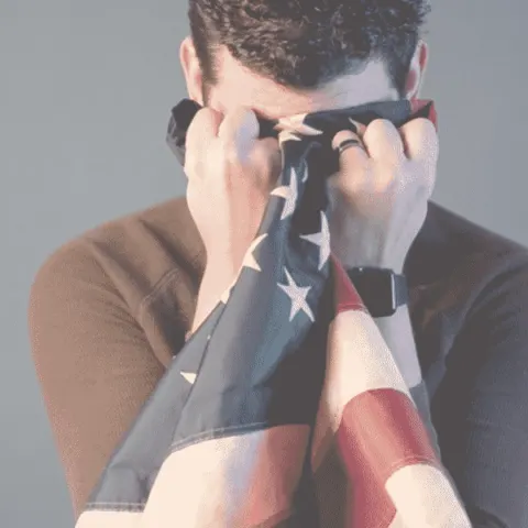 Patriot holding an American flag close, symbolizing faith and national pride.