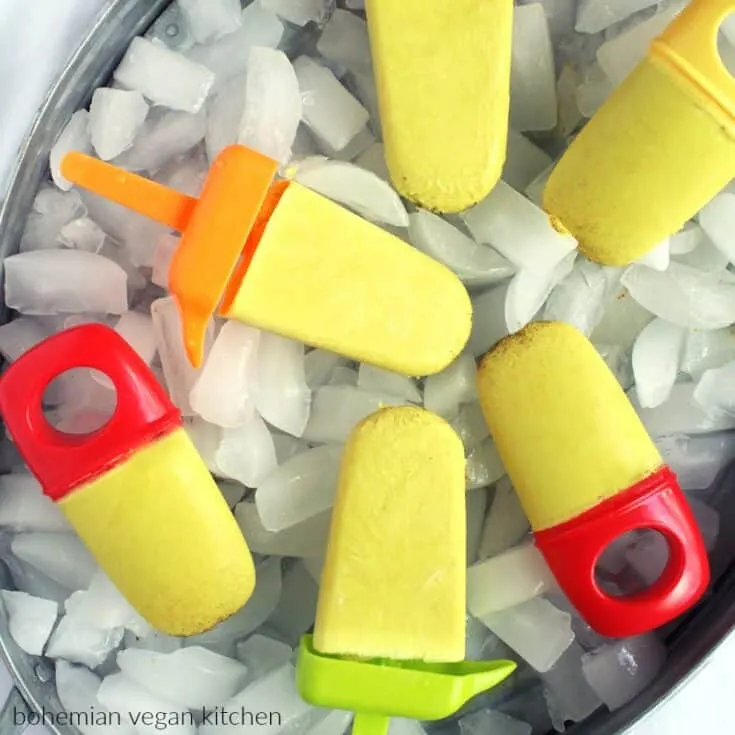 Colorful popsicles on ice with red, yellow, green, and orange handles.
