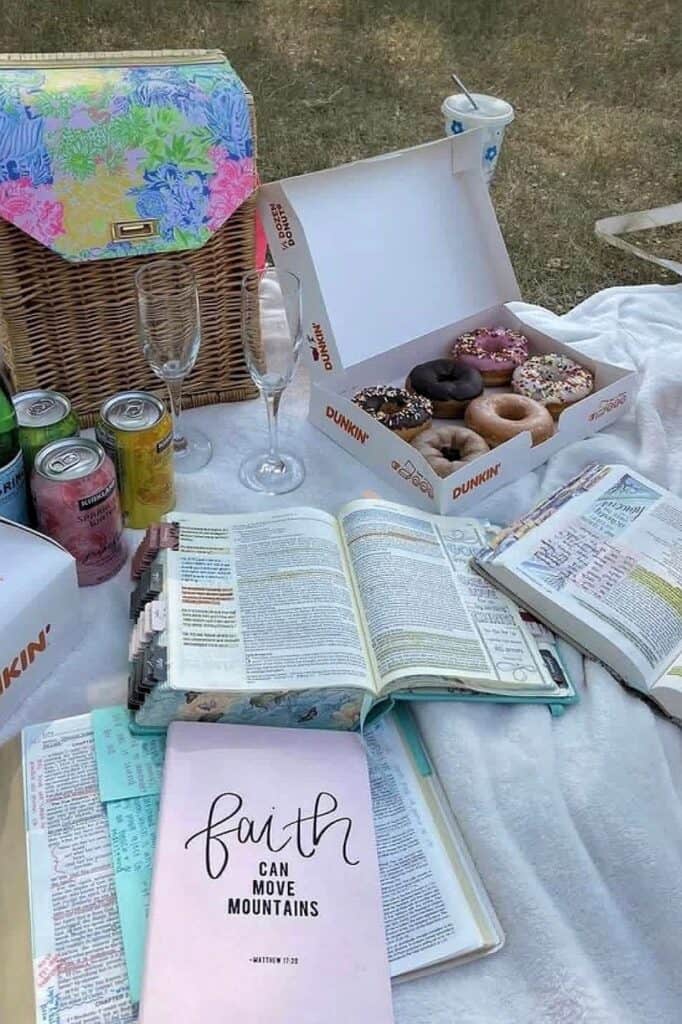Outdoor picnic setup with donuts, drinks, and open Bible for Bible study.