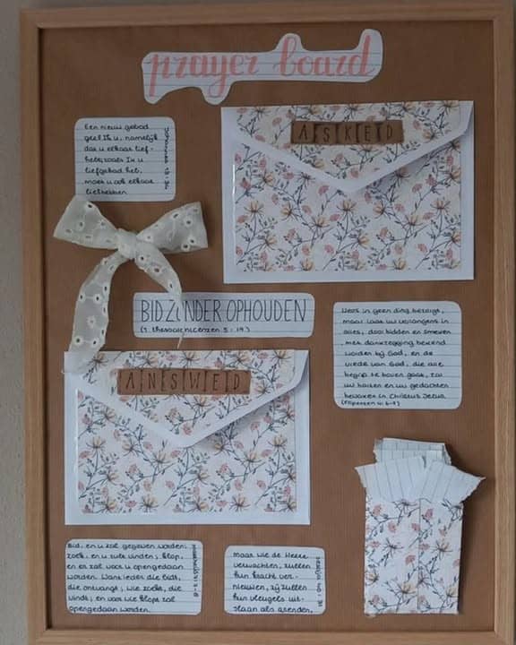 Prayer board with floral envelopes, notes, and decorative ribbon for faith reflection.