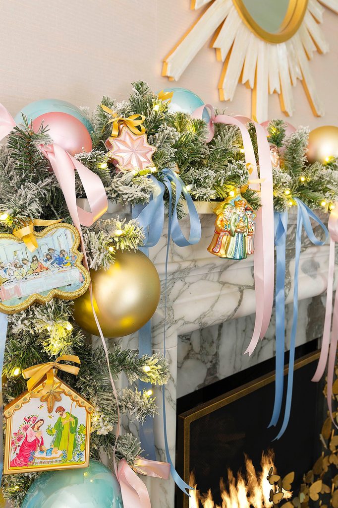 Festive Christmas garland with ornaments, ribbons, and lights above fireplace.