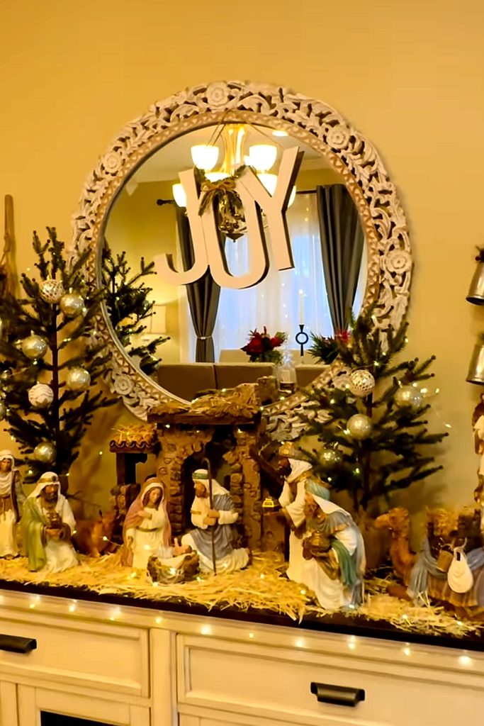 Nativity scene with Christmas trees and festive decorations in a living room.