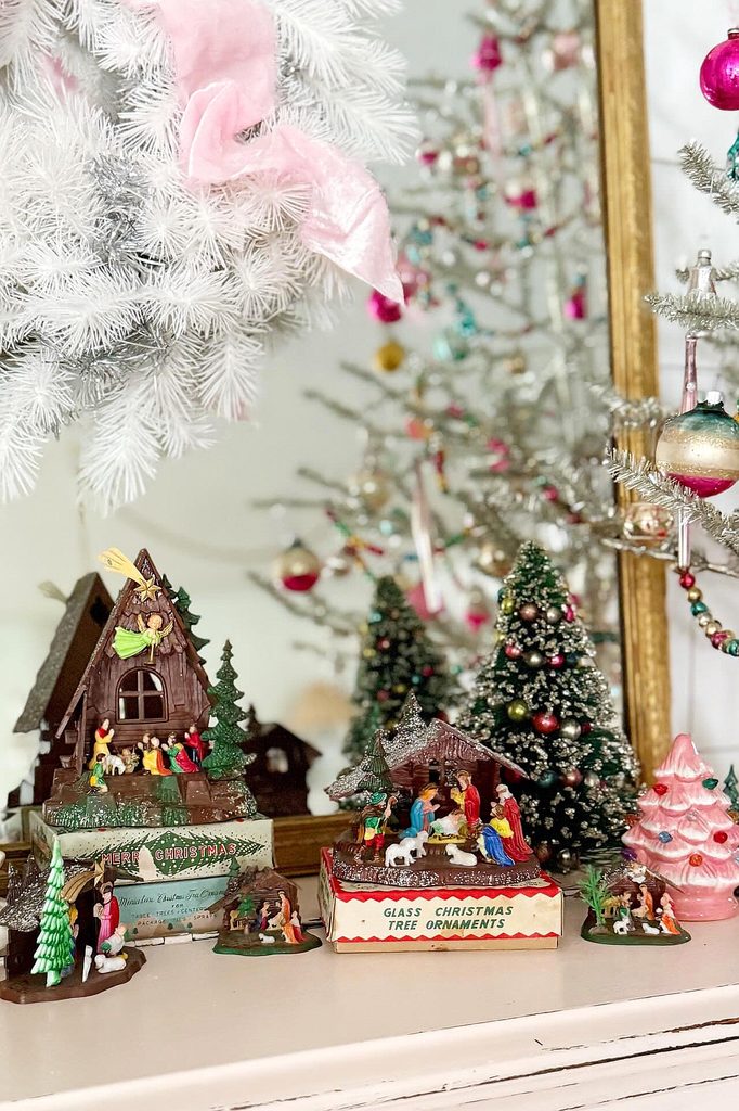 Festive nativity scene with miniature figures under decorated Christmas trees.