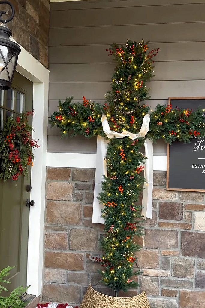 Festive Christmas cross decorated with lights and greenery for holiday celebration.